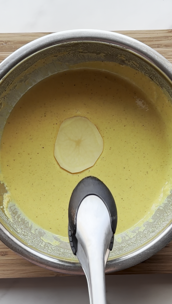 slice of potato being put into the batter for Afghan Pakawra